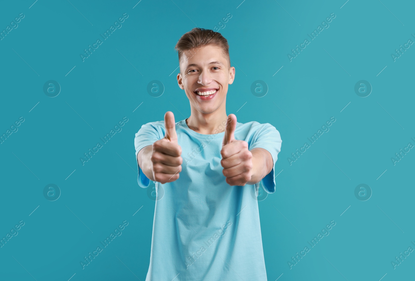 Photo of Happy man showing thumbs up on light blue background. Like gesture