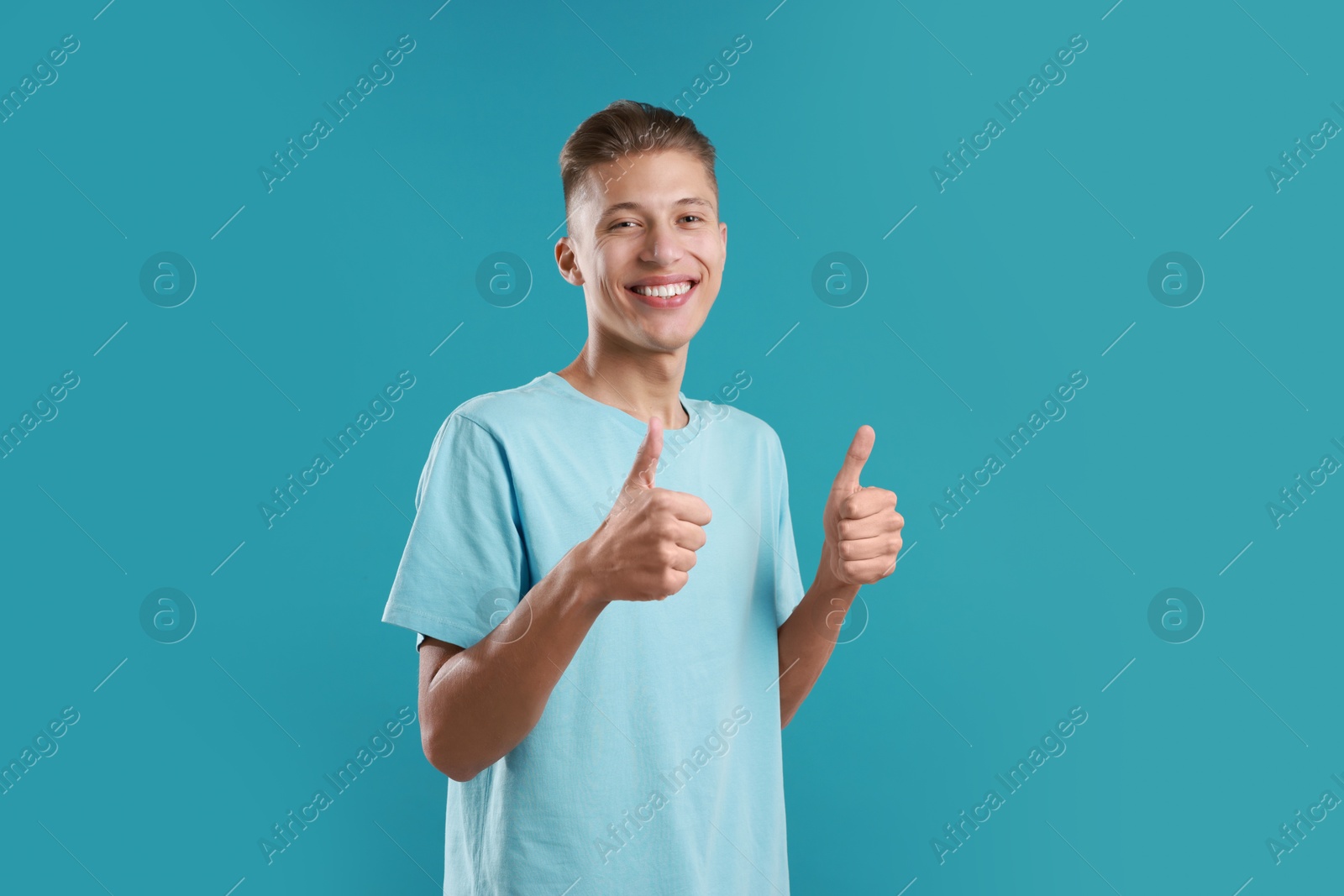 Photo of Happy man showing thumbs up on light blue background. Like gesture