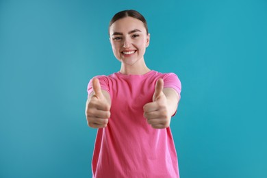 Photo of Happy woman showing thumbs up on light blue background. Like gesture