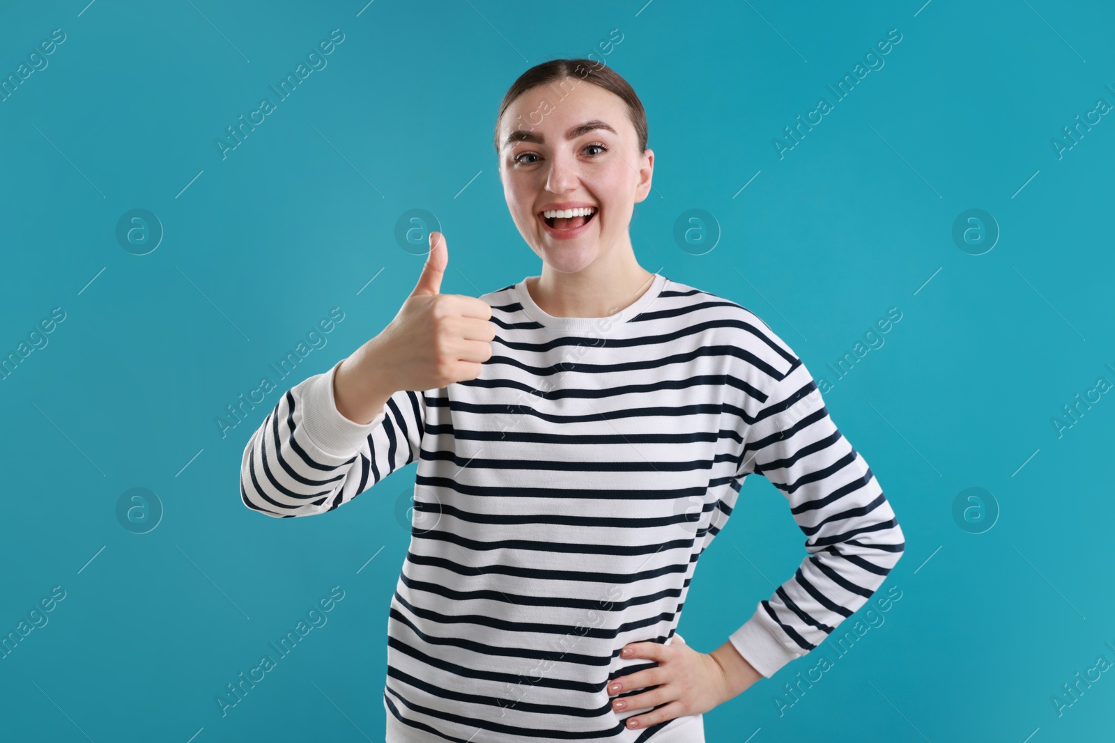 Photo of Happy woman showing thumbs up on light blue background. Like gesture