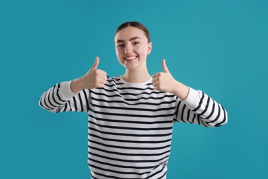 Photo of Happy woman showing thumbs up on light blue background. Like gesture