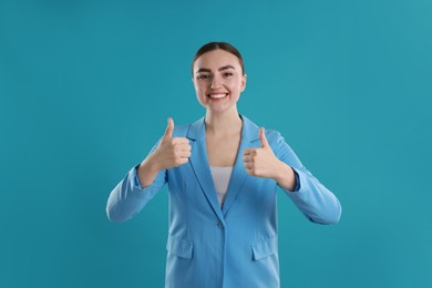 Photo of Happy woman showing thumbs up on light blue background. Like gesture