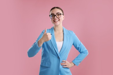 Happy woman showing thumbs up on pink background. Like gesture