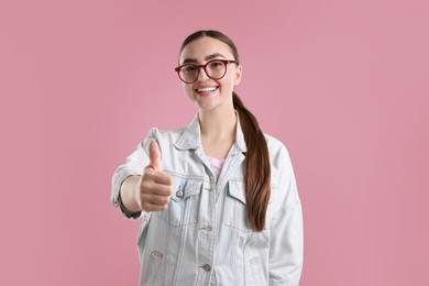 Photo of Happy woman showing thumbs up on pink background. Like gesture