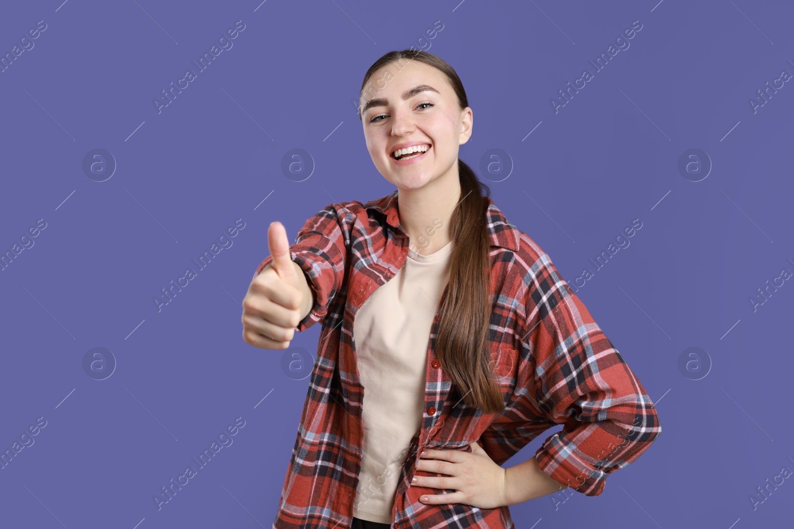 Photo of Happy woman showing thumbs up on purple background. Like gesture