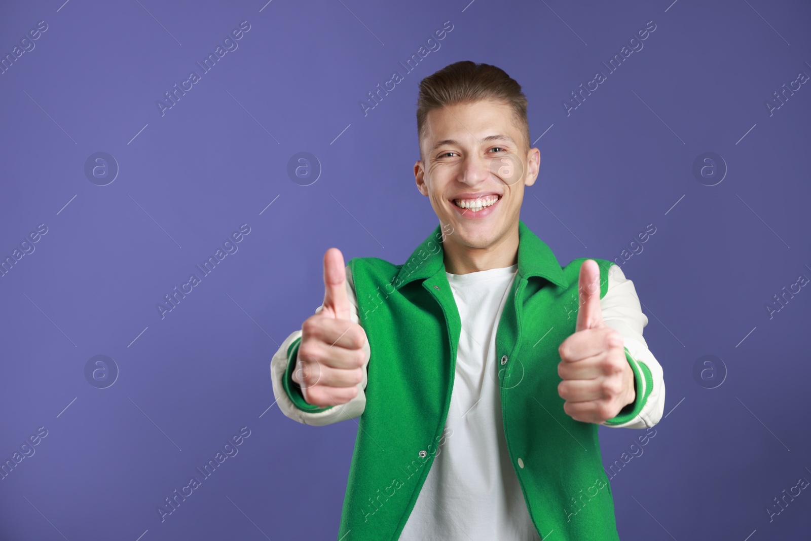 Photo of Happy man showing thumbs up on purple background, space for text. Like gesture