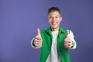 Happy man showing thumbs up on purple background, space for text. Like gesture