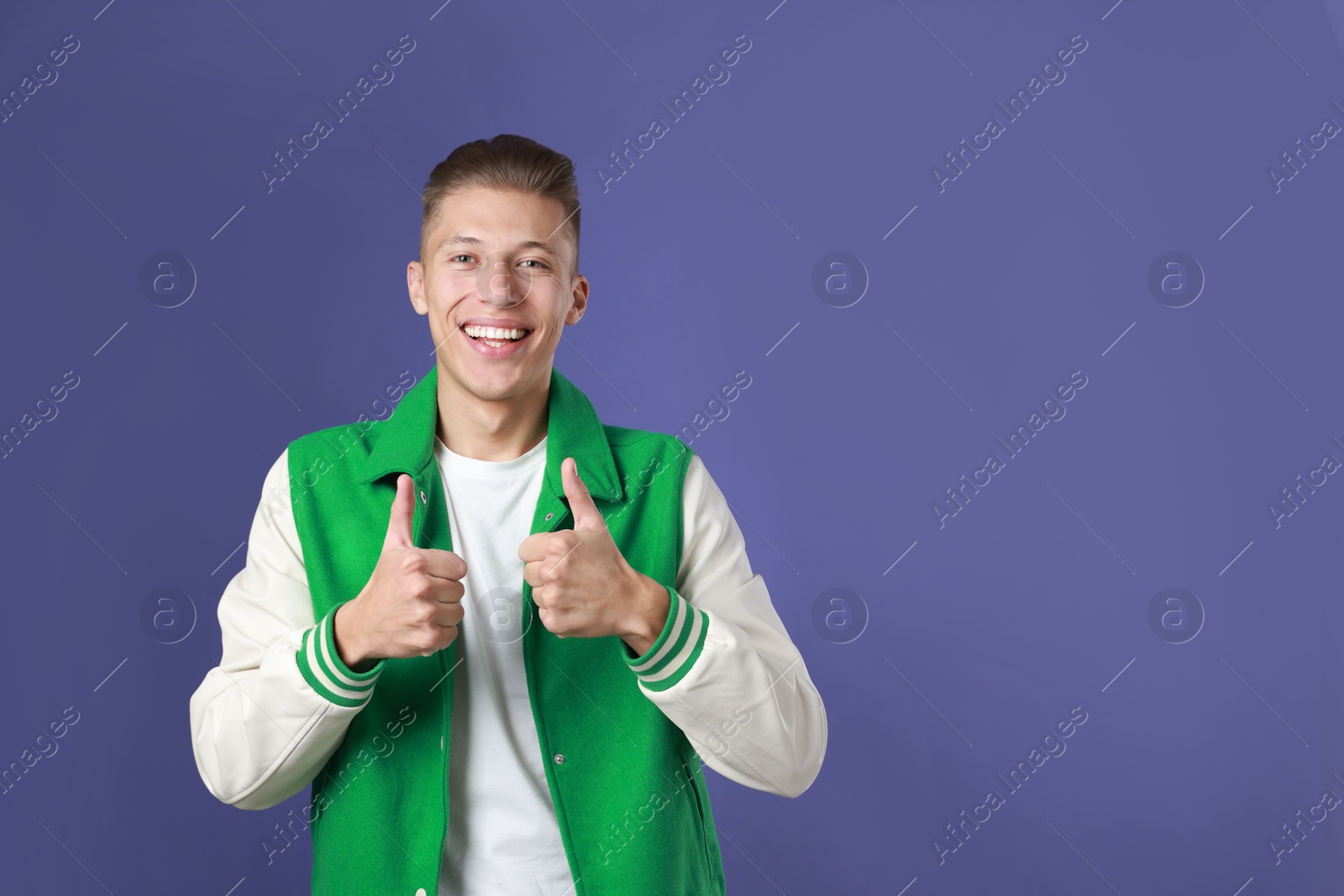 Photo of Happy man showing thumbs up on purple background, space for text. Like gesture