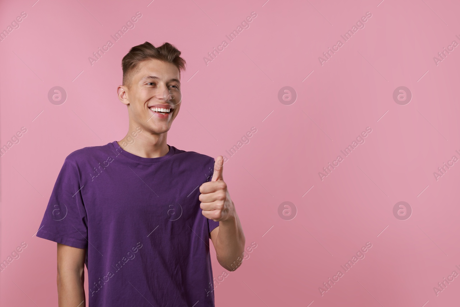 Photo of Happy man showing thumbs up on pink background, space for text. Like gesture