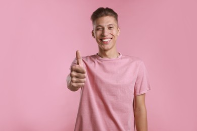 Happy man showing thumbs up on pink background. Like gesture