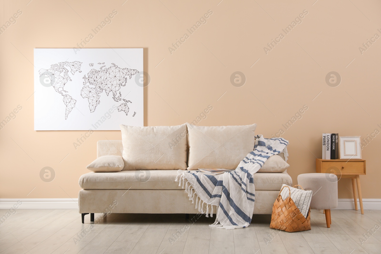 Photo of Comfortable sofa with pillows, blanket, pouf and picture indoors