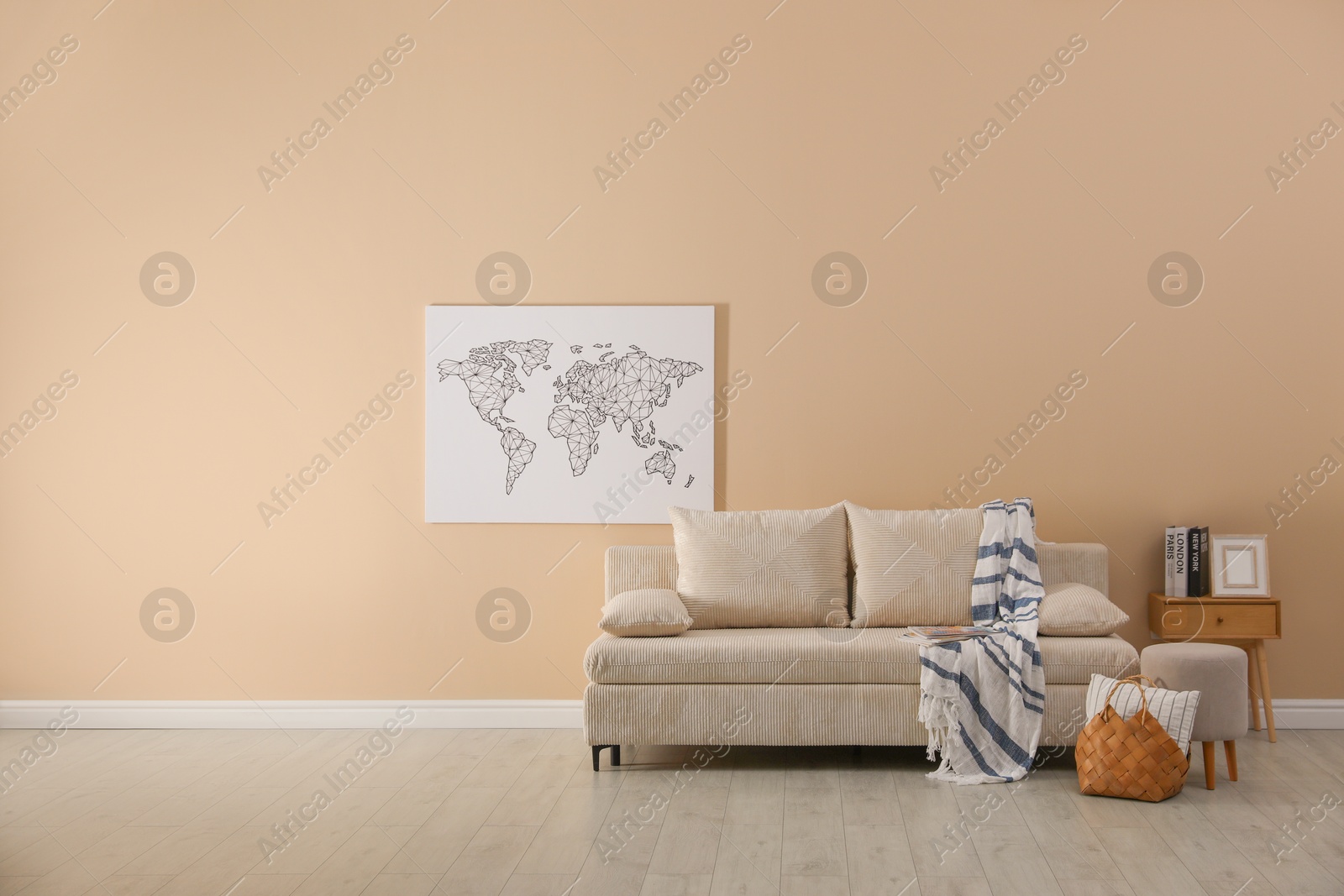 Photo of Comfortable sofa with pillows, blanket, pouf and picture indoors, space for text