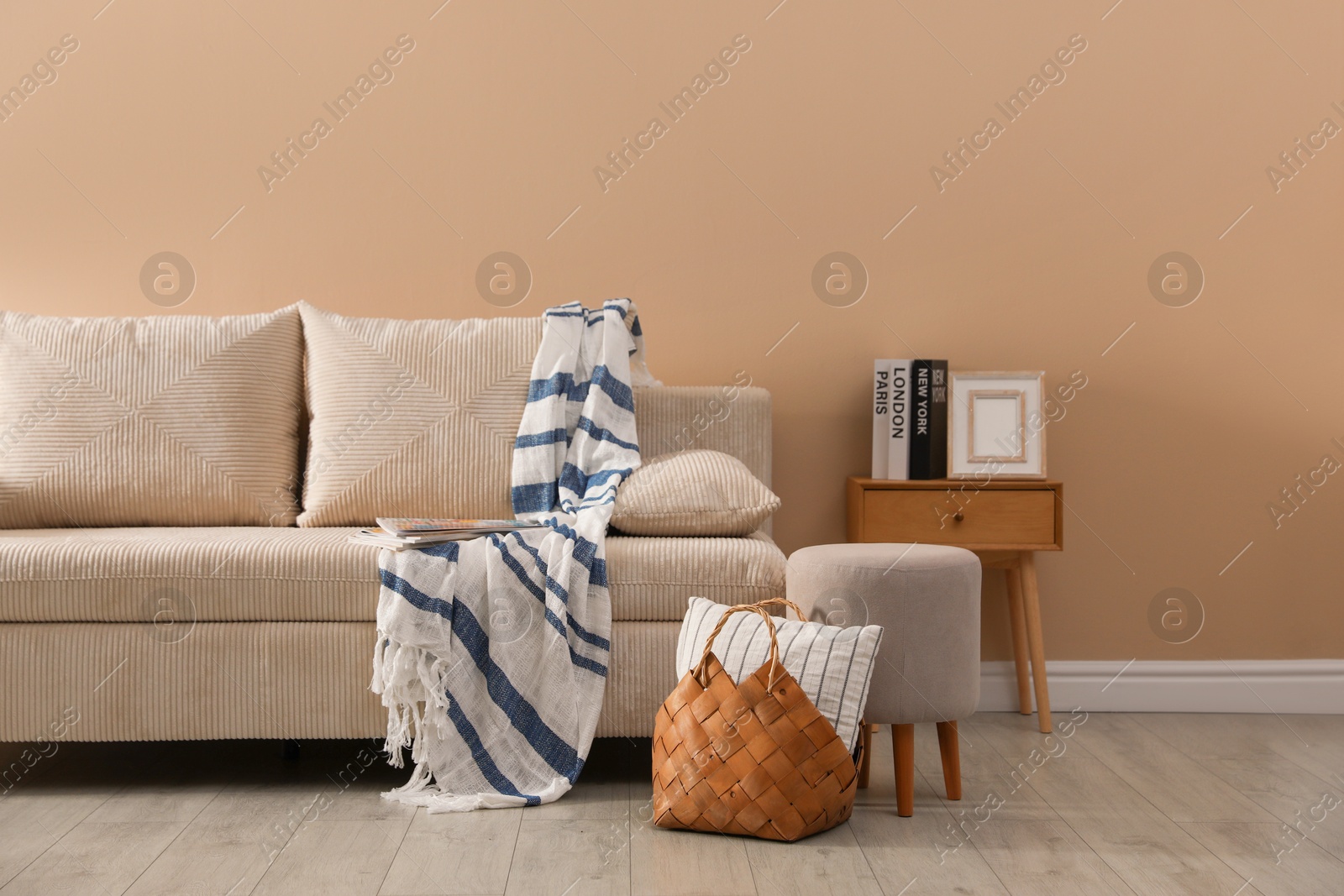 Photo of Comfortable sofa with pillows, blanket, pouf and bag indoors