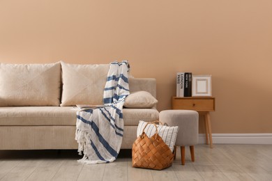 Photo of Comfortable sofa with pillows, blanket, pouf and bag indoors