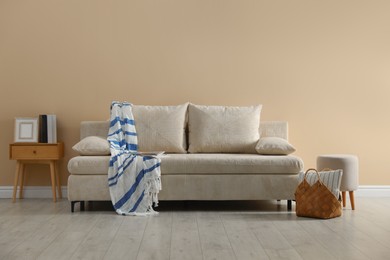 Photo of Comfortable sofa with pillows, blanket, pouf and bag indoors