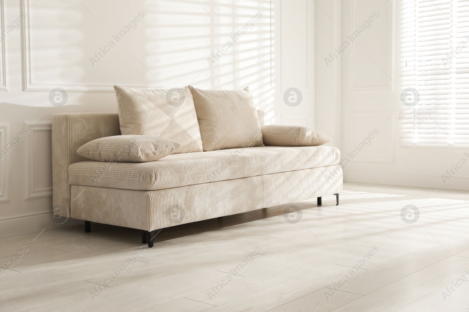 Photo of Comfortable sofa with pillows in light room