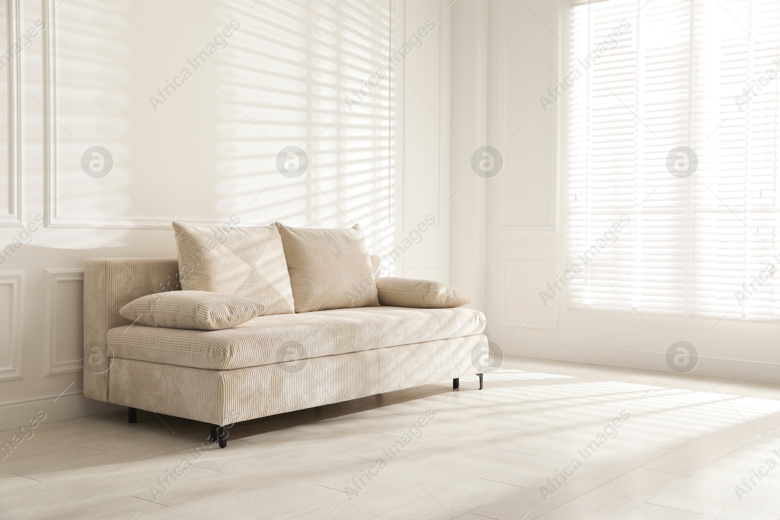 Photo of Comfortable sofa with pillows in light room