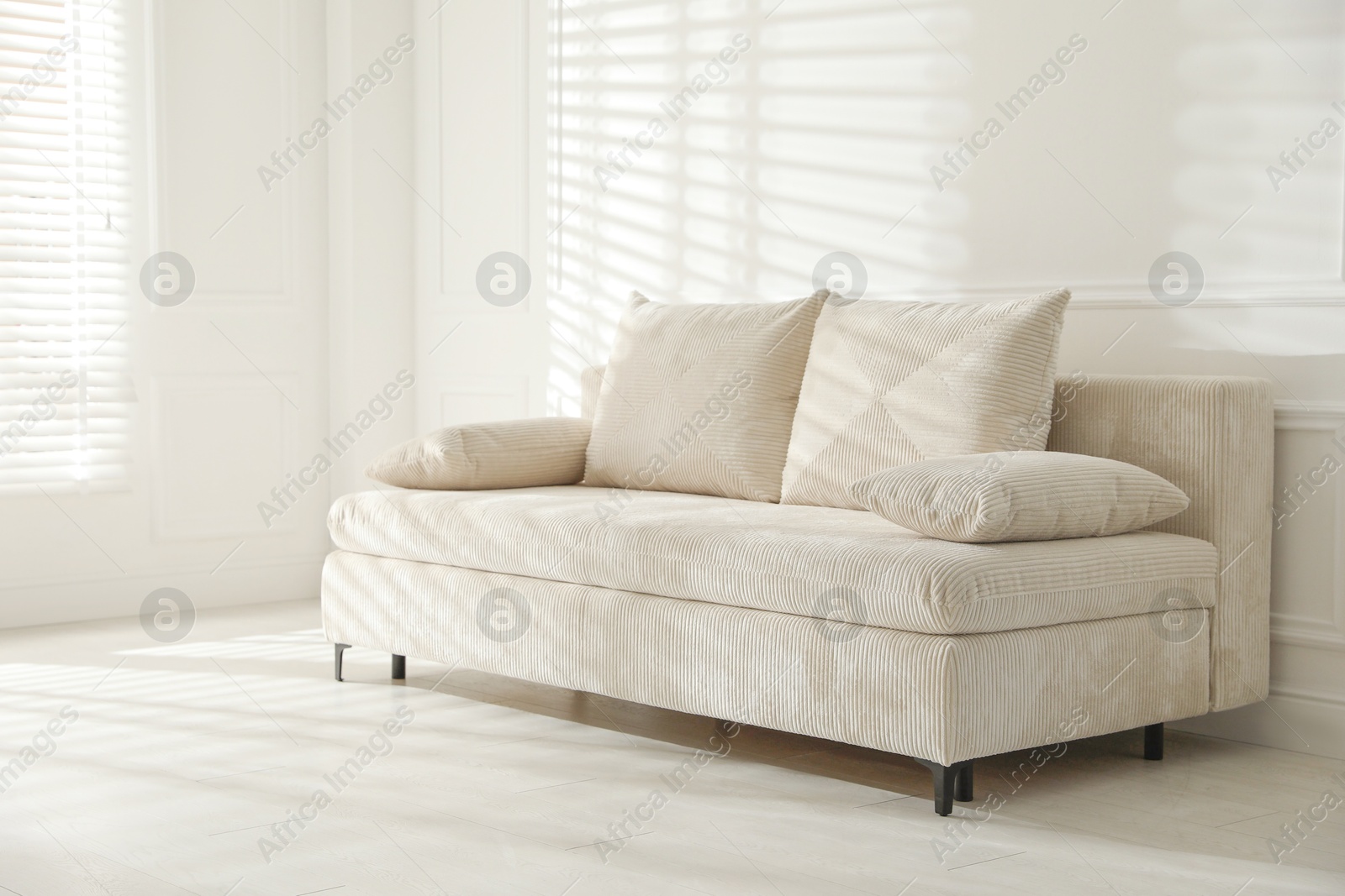 Photo of Comfortable sofa with pillows in light room