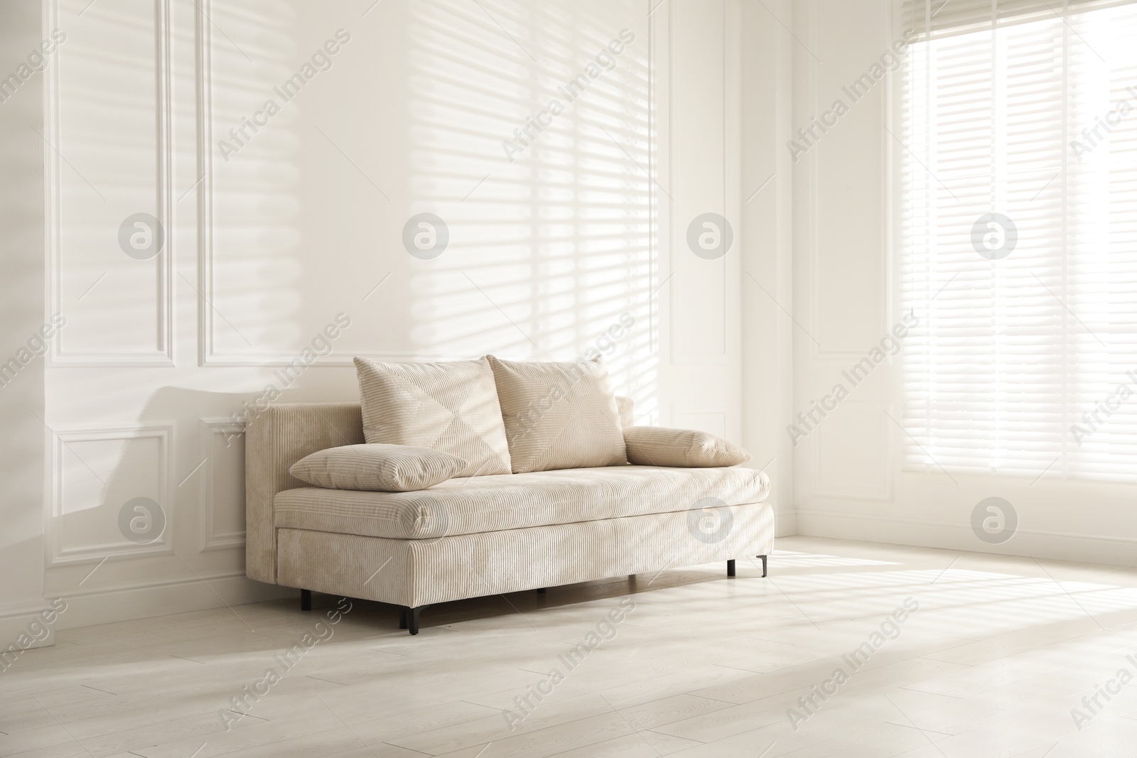 Photo of Comfortable sofa with pillows in light room