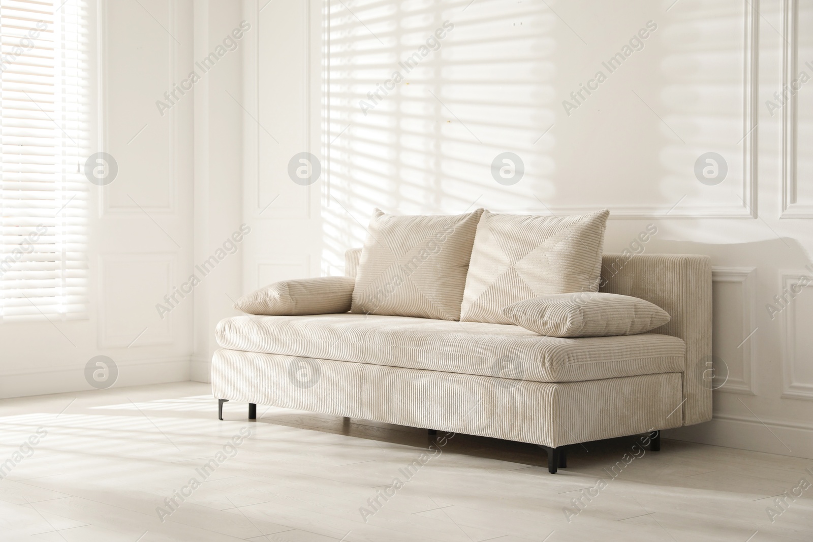 Photo of Comfortable sofa with pillows in light room