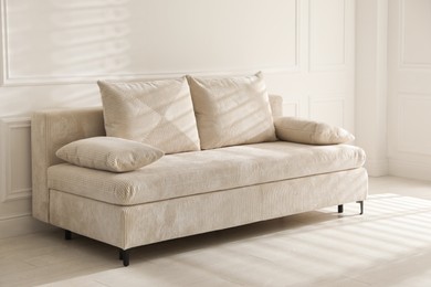 Photo of Comfortable sofa with pillows in light room