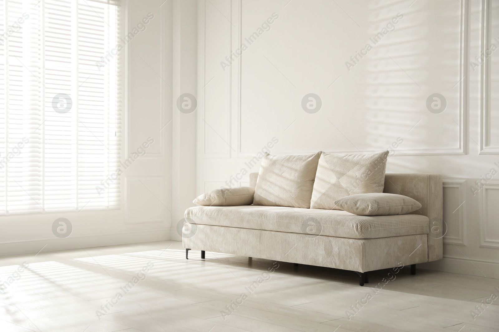 Photo of Comfortable sofa with pillows in light room