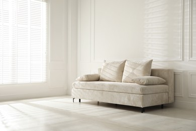 Photo of Comfortable sofa with pillows in light room