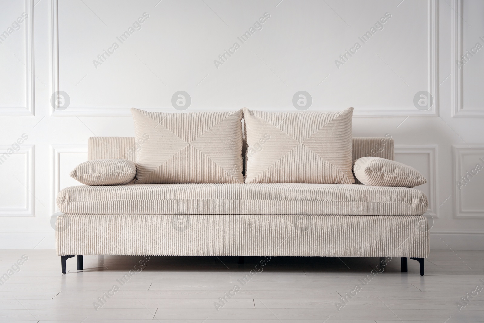 Photo of Comfortable sofa with pillows near white wall indoors