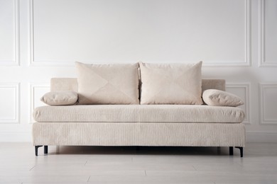 Photo of Comfortable sofa with pillows near white wall indoors