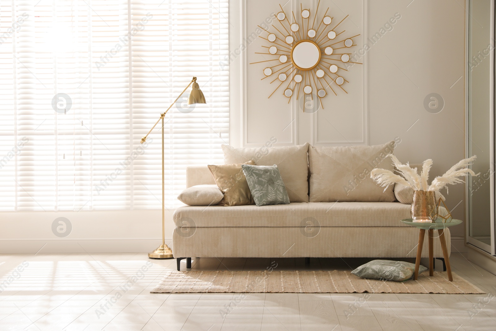 Photo of Comfortable sofa with pillows, lamp and different decor in room. Interior design