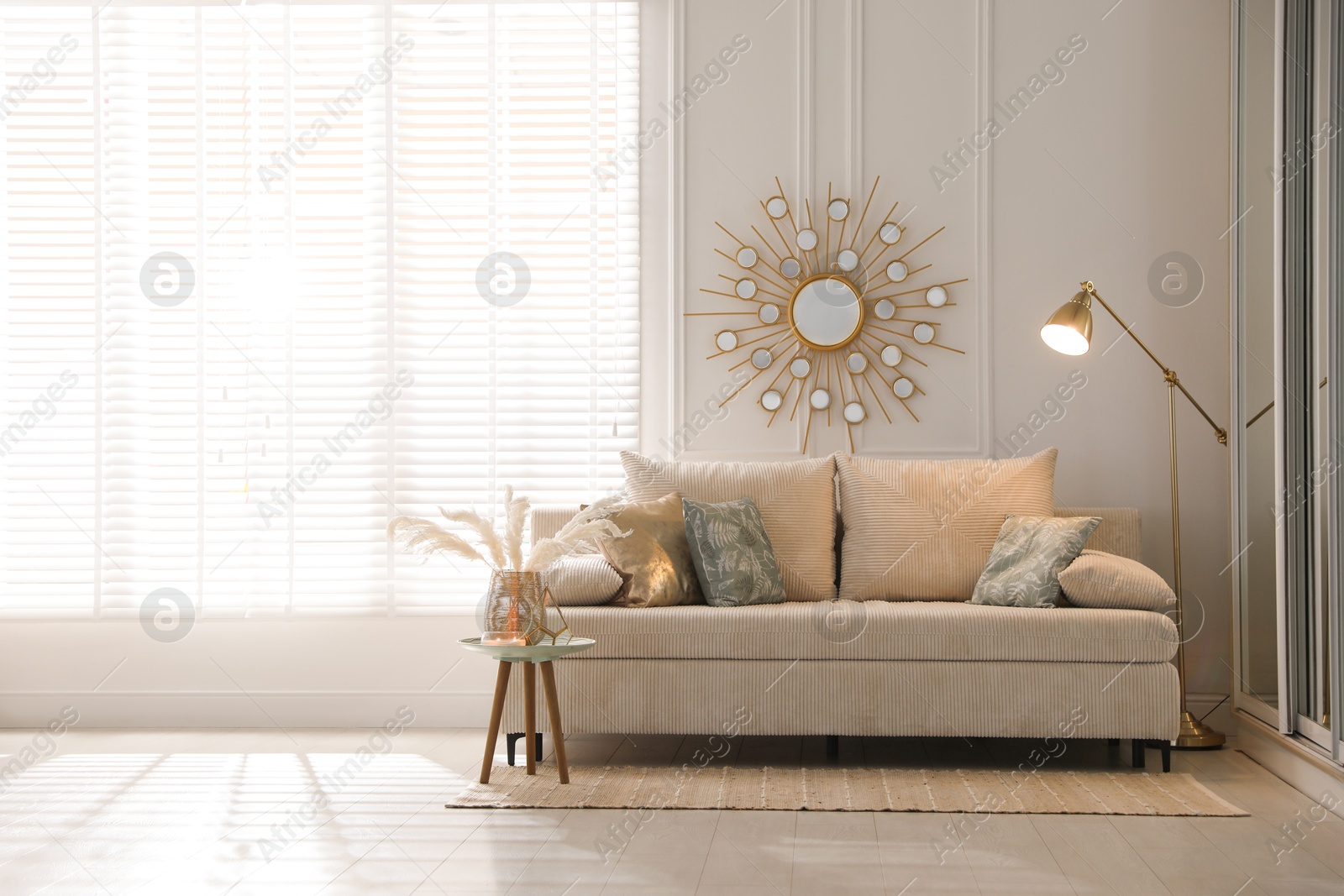 Photo of Comfortable sofa with pillows, lamp and different decor in room. Interior design