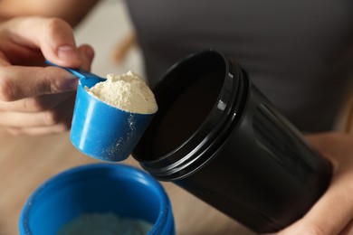 Photo of Making protein cocktail. Man adding powder into shaker at table, closeup