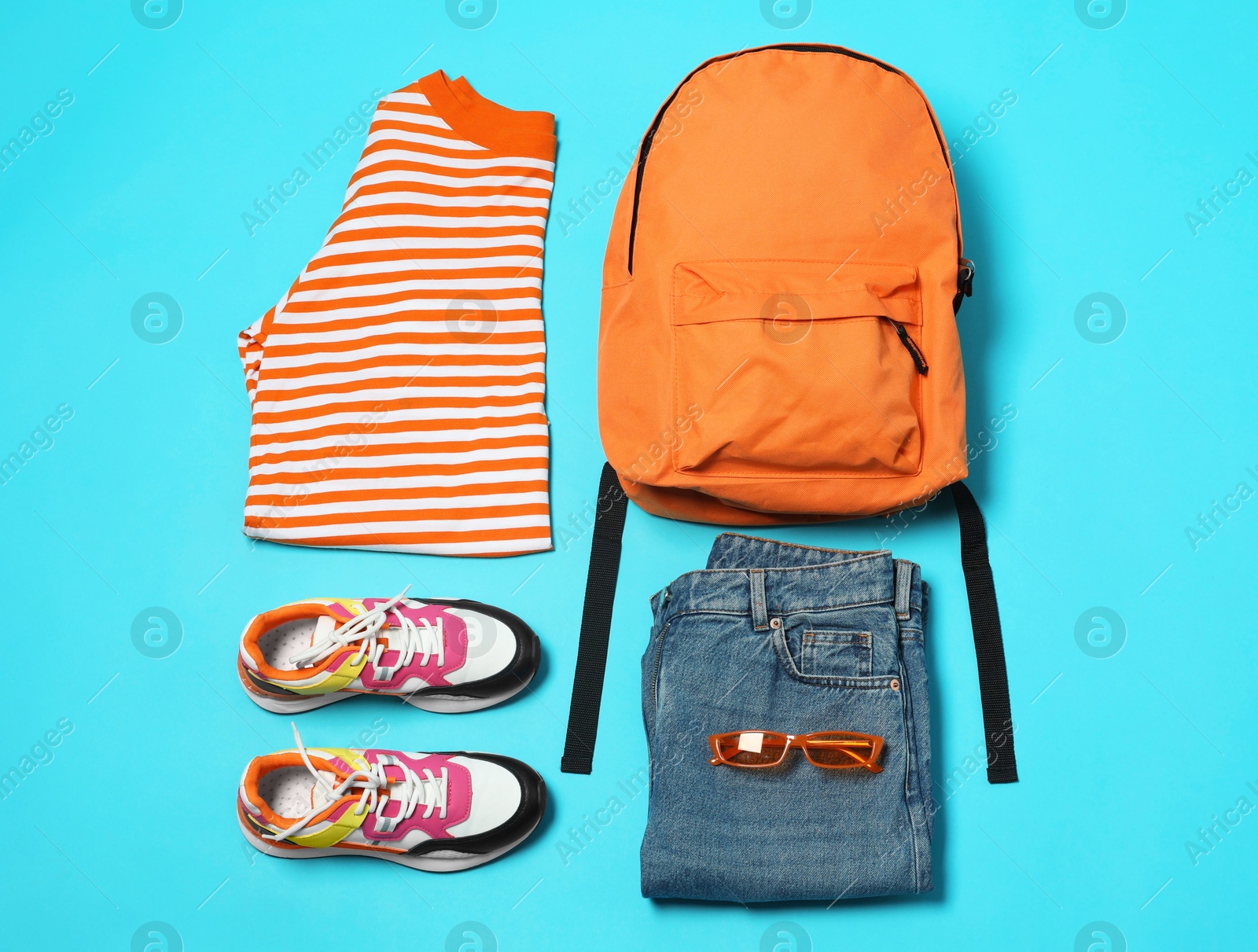 Photo of Stylish outfit with backpack on light blue background, flat lay