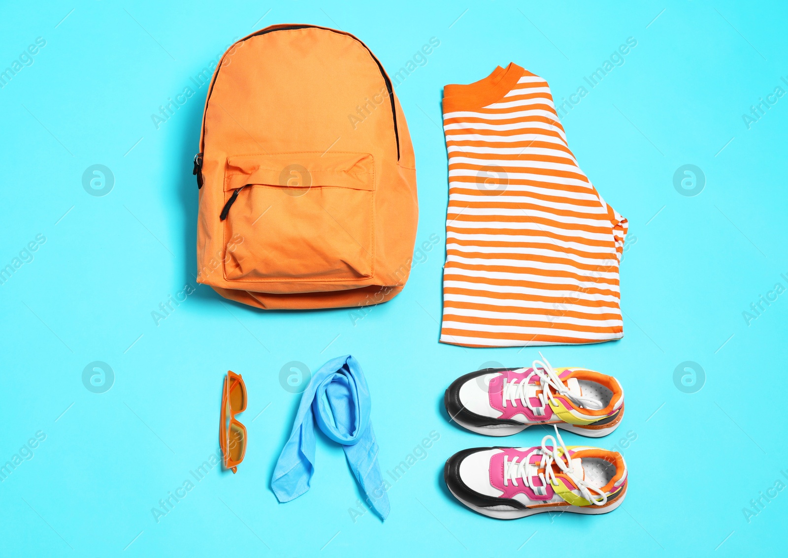 Photo of Stylish outfit with backpack on light blue background, flat lay