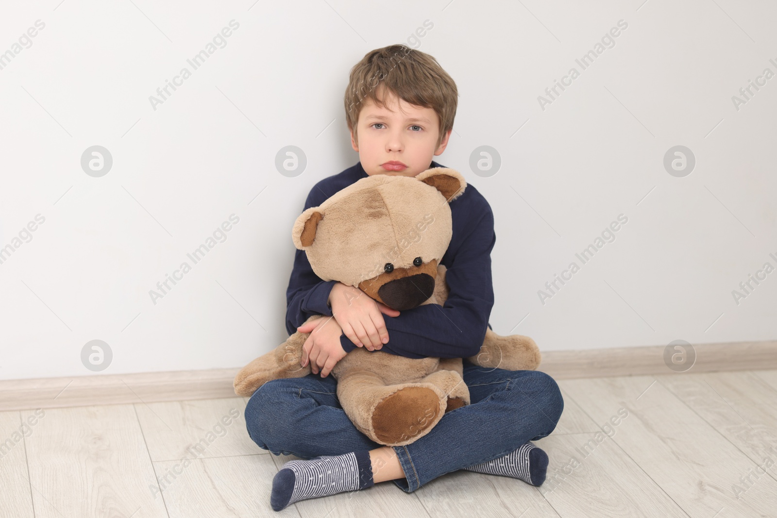 Photo of Autism concept. Lonely little boy with teddy bear on floor at home