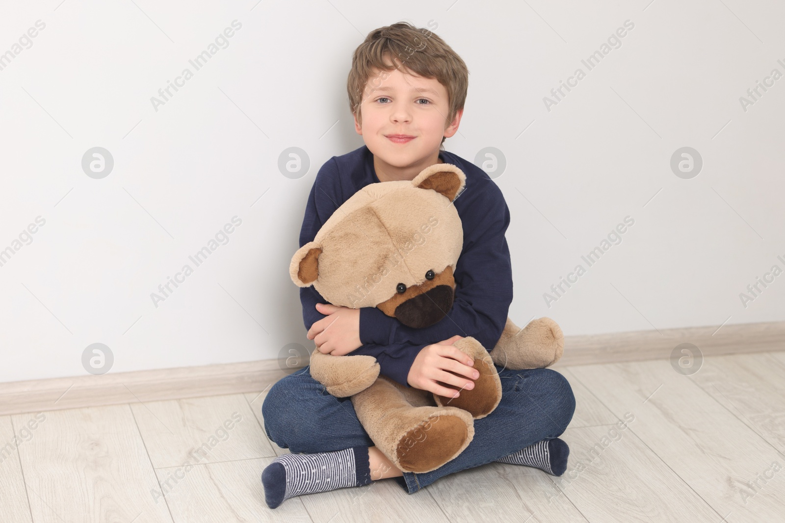 Photo of Autism concept. Lonely little boy with teddy bear on floor at home