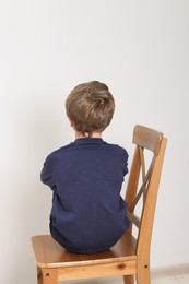 Photo of Autism concept. Lonely little boy on chair at home, back view