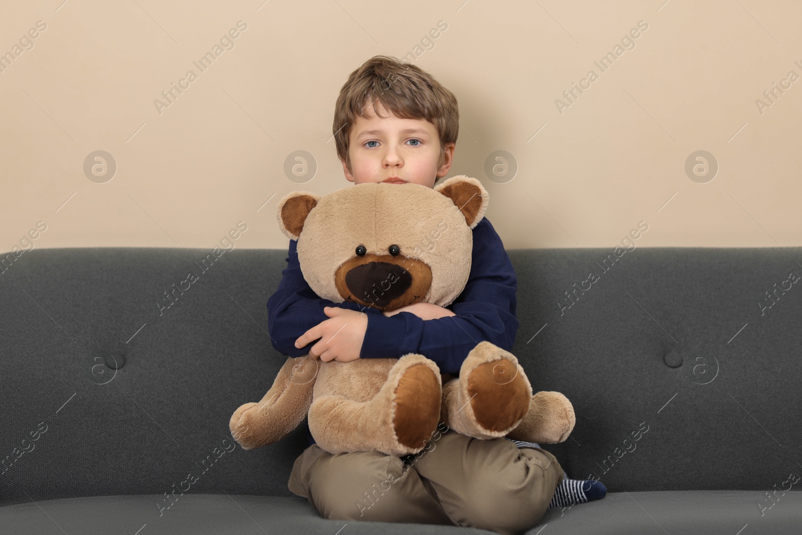 Photo of Autism concept. Lonely little boy with teddy bear on sofa at home