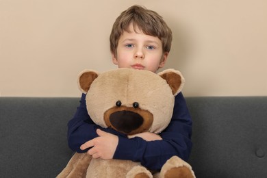 Photo of Autism concept. Lonely little boy with teddy bear on sofa at home