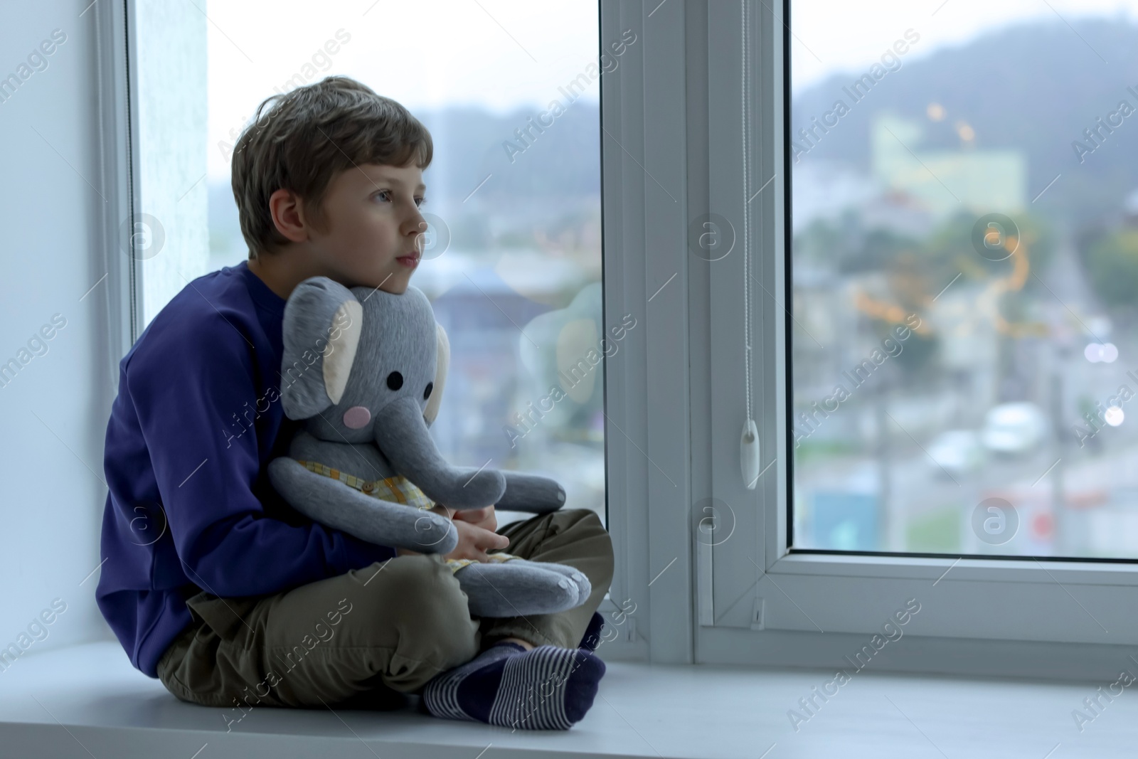 Photo of Autism concept. Lonely little boy with toy elephant near window at home