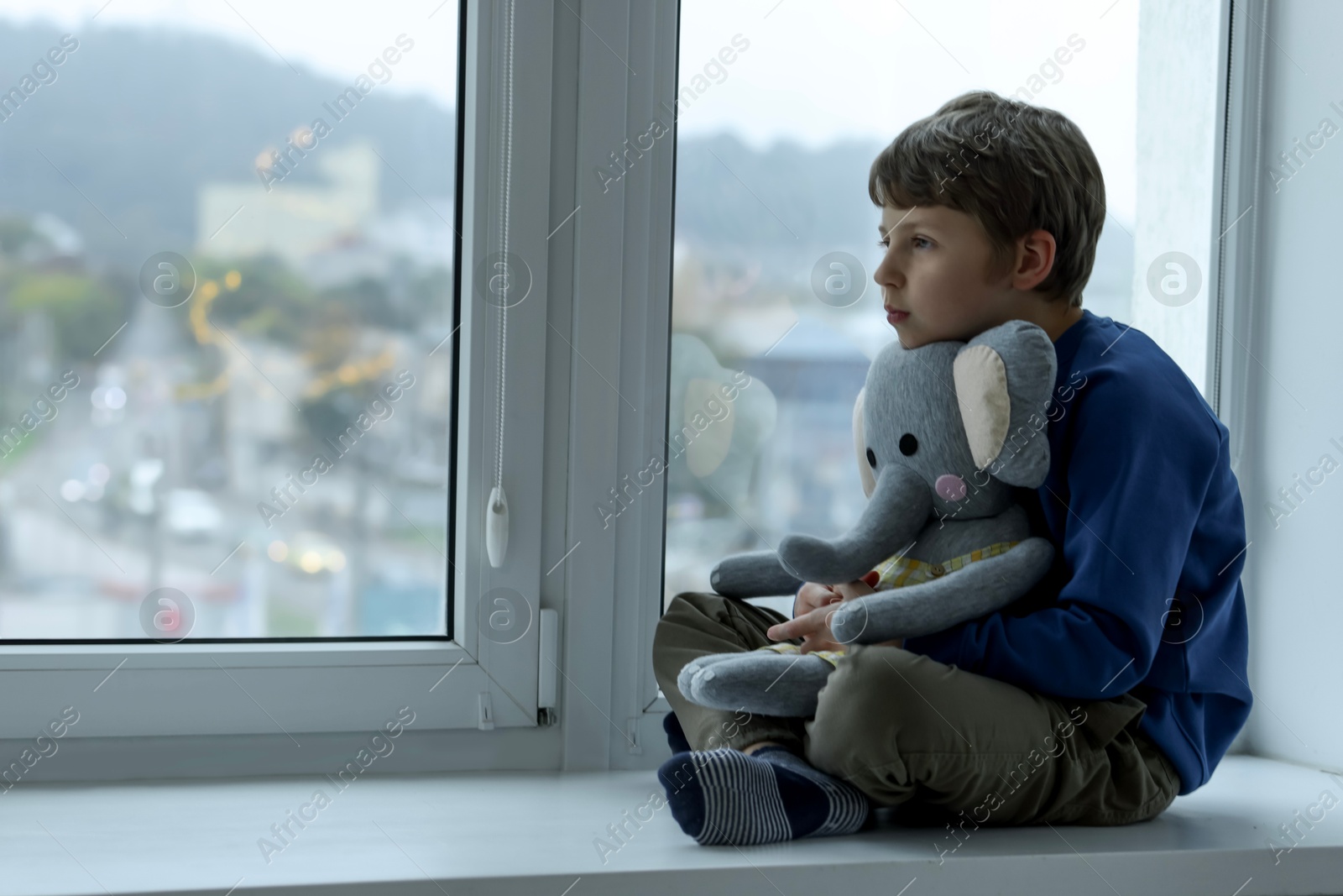 Photo of Autism concept. Lonely little boy with toy elephant near window at home