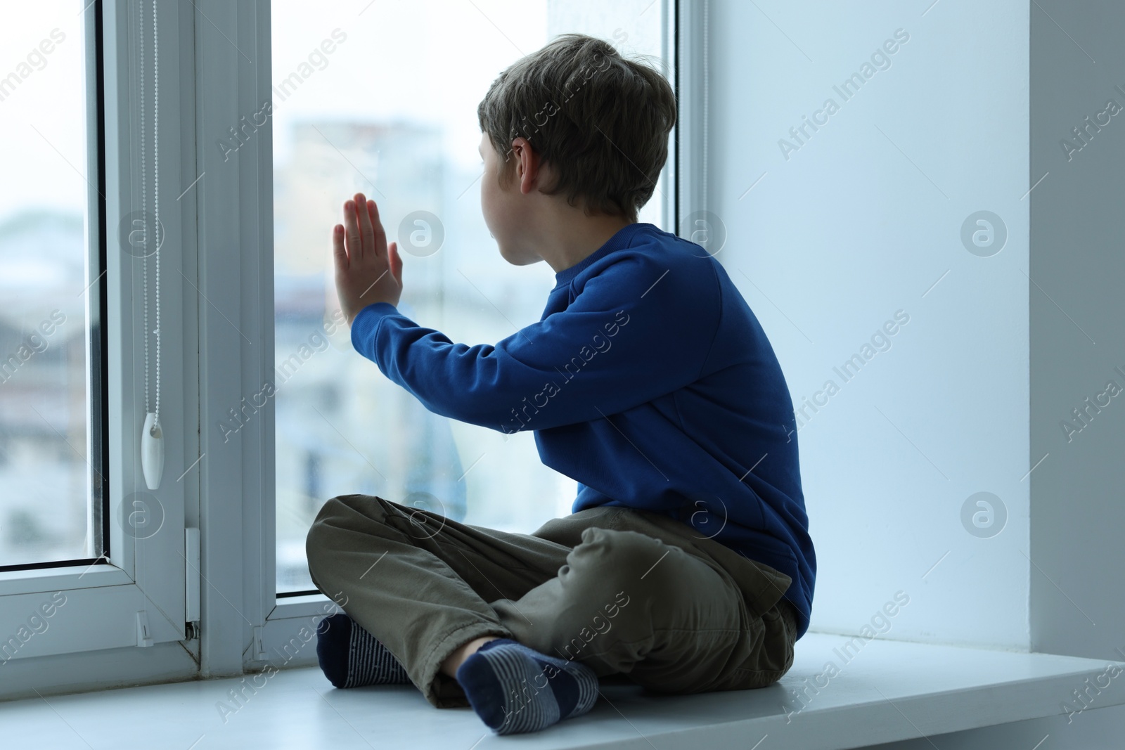 Photo of Autism concept. Lonely little boy near window at home