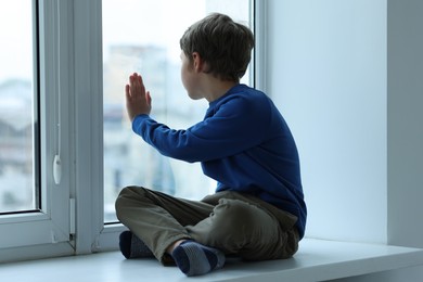 Photo of Autism concept. Lonely little boy near window at home