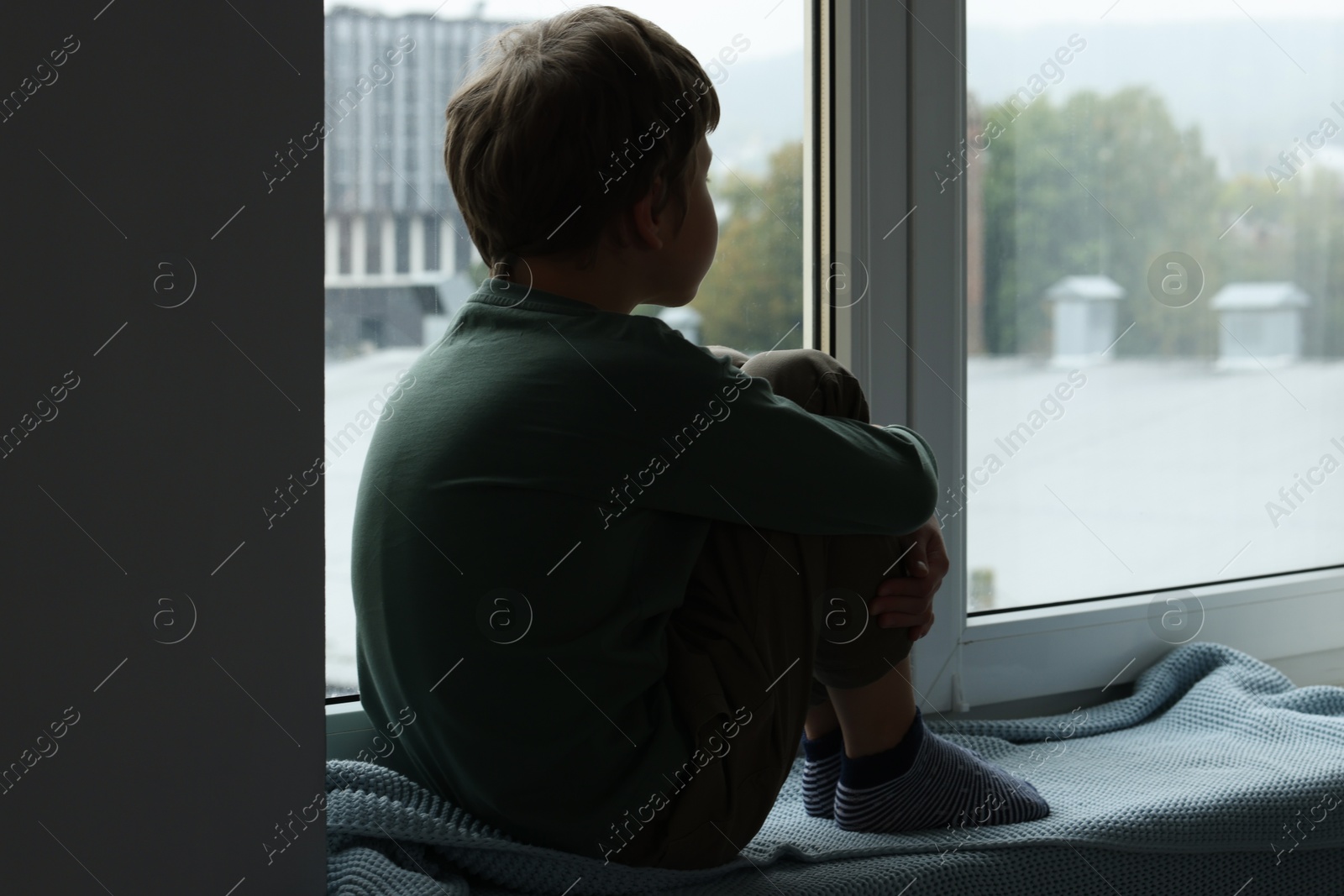 Photo of Autism concept. Lonely little boy near window at home