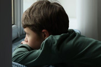 Photo of Autism concept. Lonely little boy near window at home