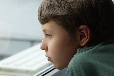 Photo of Autism concept. Lonely little boy near window at home, space for text