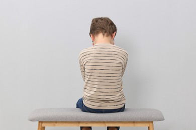 Photo of Autism concept. Lonely little boy on bench at home, back view