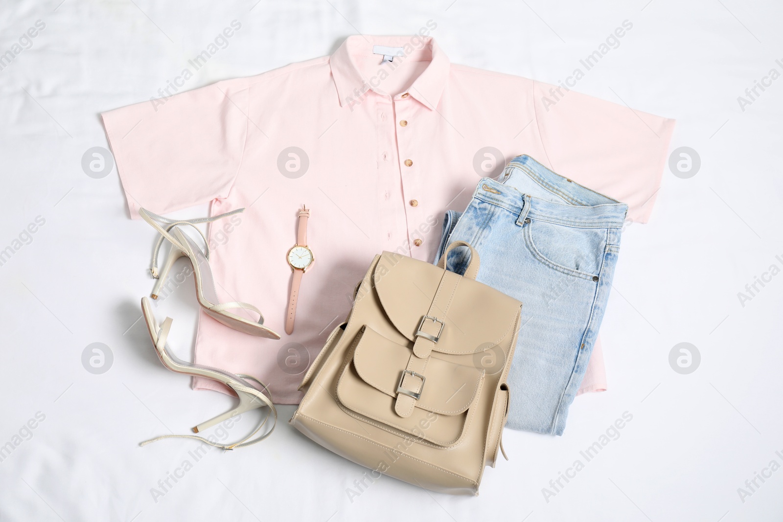 Photo of Stylish outfit with backpack on white fabric, flat lay