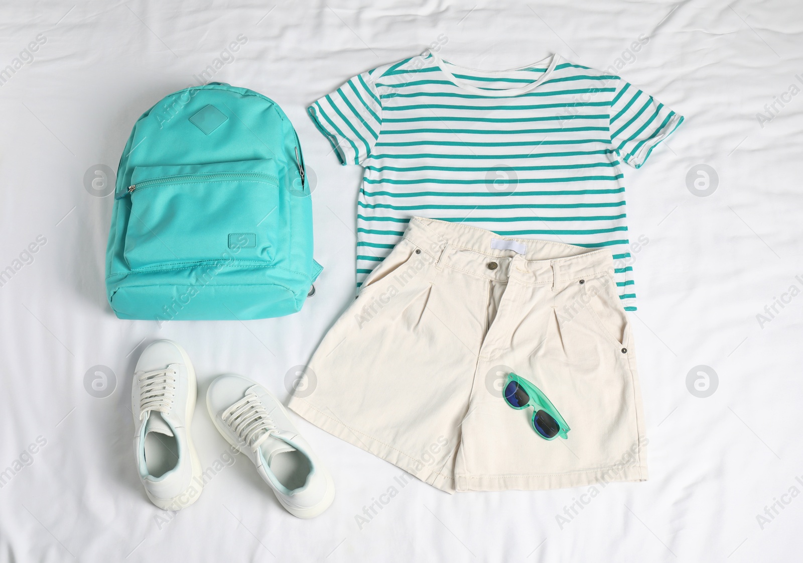 Photo of Stylish outfit with backpack on white fabric, flat lay