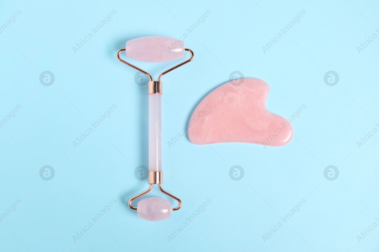 Photo of Face roller and gua sha tool on light blue background, top view